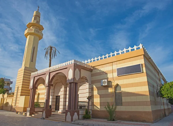 Entrance to old egyptian mosque building with minaret against blue sky background
