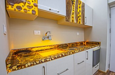 İç epoksi reçine ve ahşap ağaç blokları tasarımı modern mutfağı dolaplarla ve lüks apartman galerisinde lavaboyla gösteriyor.