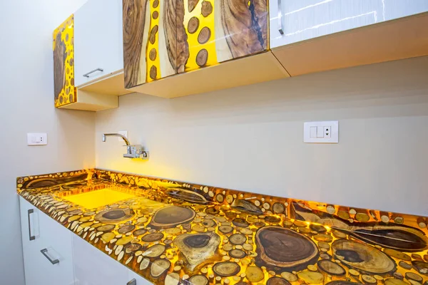 高級アパートのショールームで食器棚とシンクとモダンなキッチンを示すインテリアエポキシ樹脂と木製の木のブロックのデザインの装飾 — ストック写真