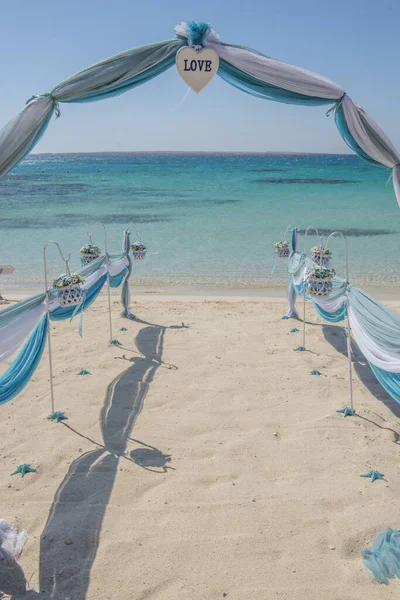 ドレープ付きの結婚式の日の結婚通路のセットアップと海の背景を開くために砂浜の熱帯のビーチの楽園のアーチ — ストック写真