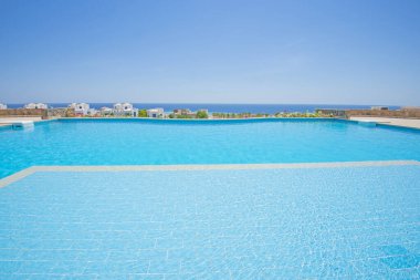 Lüks bir tropikal otel tesisinde deniz manzaralı büyük bir sonsuzluk yüzme havuzu.