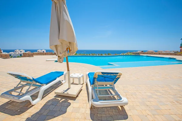 位于热带豪华酒店度假胜地的大型室外游泳池 有日光浴床和海景 — 图库照片