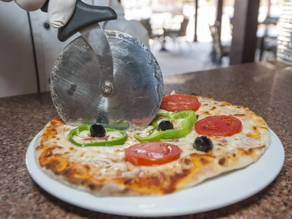 Pizza being cut into slices — Stock Photo, Image