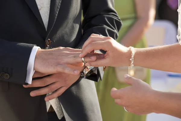 Bride putting ring on grooms finger — Stock Photo, Image