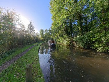 Sonbaharda mavi gökyüzü ve İngiliz su yolu kanalı üzerinde İngiliz kırsal manzarası boyunca seyahat eden dar kayık.