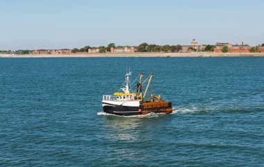 Küçük ticari balıkçı teknesi balıkçı teknesi. Mavi arka planlı sakin bir günde denize açılıyor.
