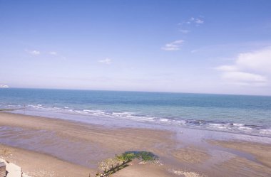 Sahil sahili manzaralı İngiliz sahili manzaralı açık mavi gökyüzü arka planı ve uzak ufukla denize bakıyor. 