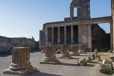 Terk edilmiş antik Roma şehir tapınağındaki sütunların kalıntıları mavi gökyüzü arka planıyla iç kısımları harabeye çeviriyor.