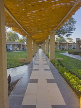 Yürüme yolunun soyut perspektifi gölgeleme örtüsü ve sütunları olan özel bahçeler boyunca uzanır.