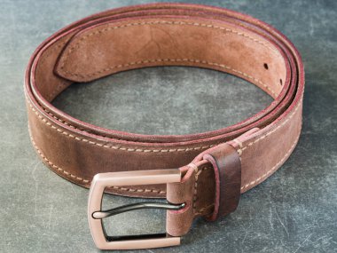 Bronz tokalı deri kemer, kemerin bir kısmı ve arkaplan bulanık.