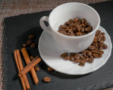 Beyaz seramik bardakta tarçınlı kahve çekirdekleri.