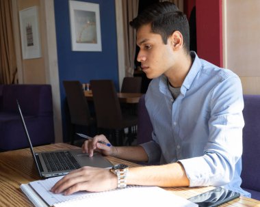 Ciddi yakışıklı üzgün bir adam, serbest çalışan, kafede defter ile çalışan üzgün, odaklanmış genç bir adam. Serbest meslek kavramı