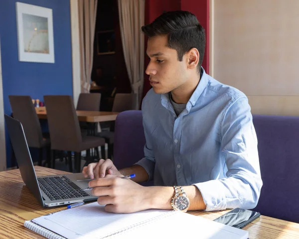 Ciddi yakışıklı, üzgün, serbest çalışan, laptopta, kafede çalışan üzgün, odaklanmış genç bir adam. Serbest meslek kavramı