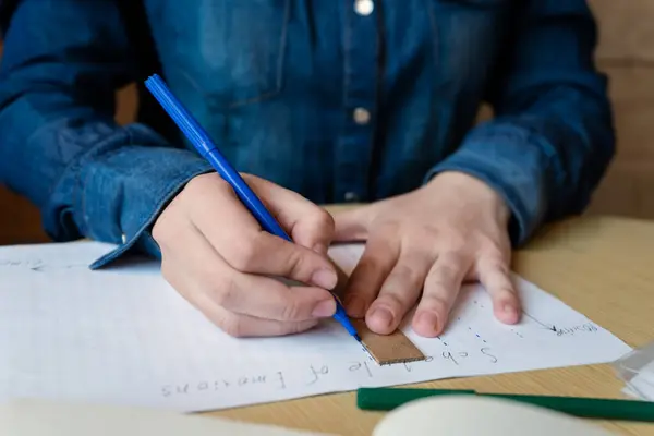 Mavi bir keçeli kalemle kız, cetvel, yeşil bir keçeli kalem ve kitap kullanarak duygu takvimi çizer masanın üzerinde, yakın plan, bir kafede fotoğraf, insan yaşam tarzı