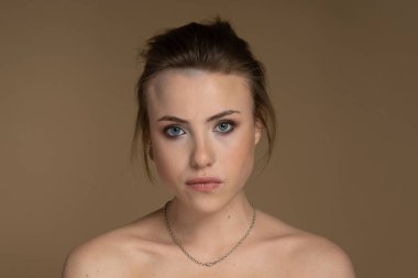 Ciddi bir alternatif modelin portresi heterokromi, kısa saç, iyi makyaj, göz kalemi, soluk ten, piercing. Önüne bak. Feminizm ve Güçlendirme. Stüdyo çekimi bej arkaplan