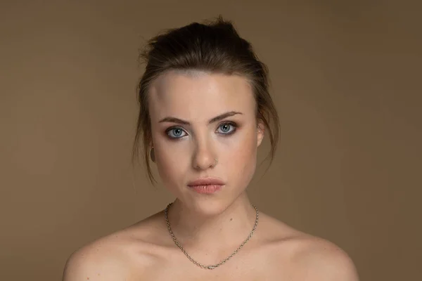 Ciddi bir alternatif modelin portresi heterokromi, kısa saç, iyi makyaj, göz kalemi, soluk ten, piercing. Önüne bak. Feminizm ve Güçlendirme. Stüdyo çekimi bej arkaplan