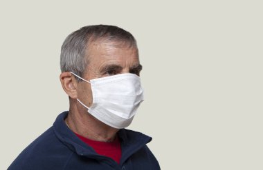 Koruyucu maske takan yaşlı bir adam.