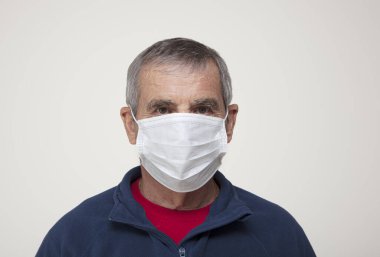 Koruyucu maske takan yaşlı bir adam.