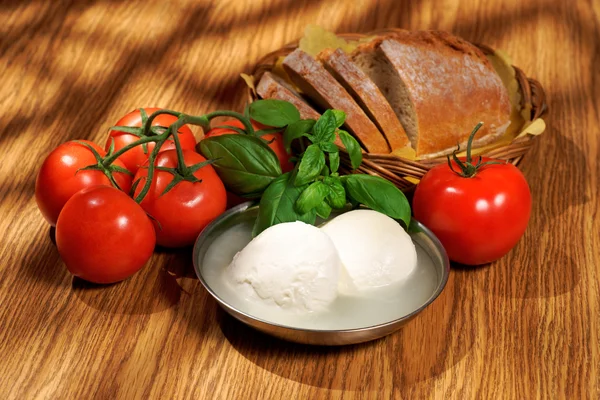 Mozzarella, rajčata, bazalka, pečivo, složení na dřevěný stůl — Stock fotografie