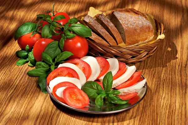 Mozzarella, tomatoes, basil, bread, composition on a wooden table — Stock Photo, Image