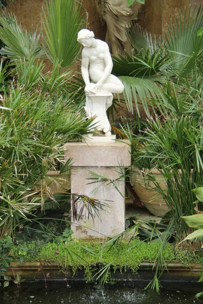 An Ornamental Statue in a Large Tropical Greenhouse.