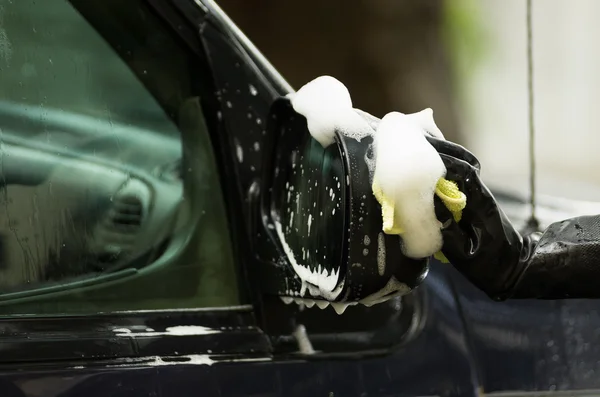 Primeros planos guantes de goma negro trabajando en el lavado de espejo lateral del coche con agua jabonosa — Foto de Stock