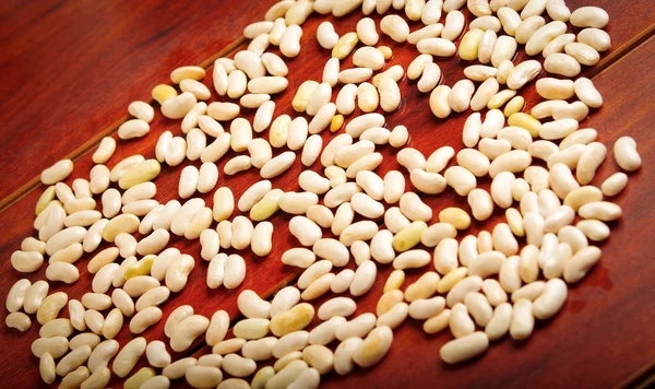 Lots of peeled lima beans lying spread out over wooden surface — Stock Photo, Image