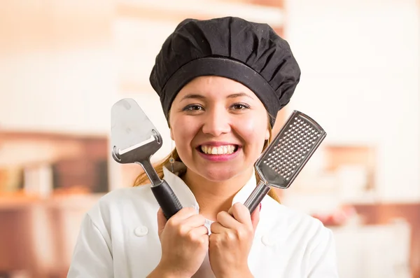 Nő szakács főzés ruhában pózol boldogan feltartotta sajt vágó és egy iratmegsemmisítő visel — Stock Fotó