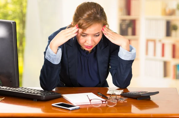 Business woman sitting by desk, elbows on table and head bent over as expressing great frustration — Stock Photo, Image