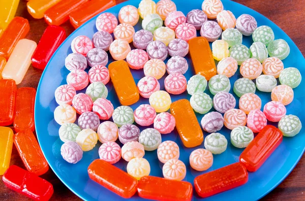 Variation of colorful hard candy lying on blue plate — Stock Photo, Image