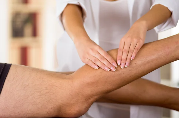 Kadın Fizyo terapist eller erkek hastalar ayak üzerinde bulanık klinik arka plan çalışma — Stok fotoğraf
