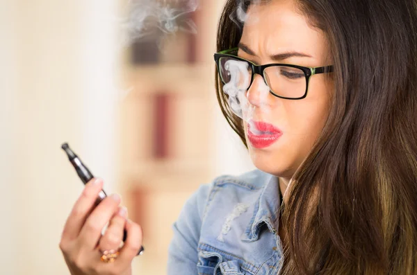 Brunette wearing glasses and bright lipstick vaping, smoking e-cigarette with smoke visible — Stock Photo, Image