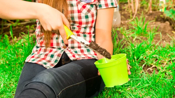 Closeup womans hands using gardening tool filling soil into green flower pot — Stock Photo, Image