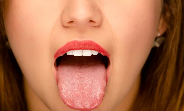 Closeup young womans open mouth with tongue sticking out — Stock Photo, Image