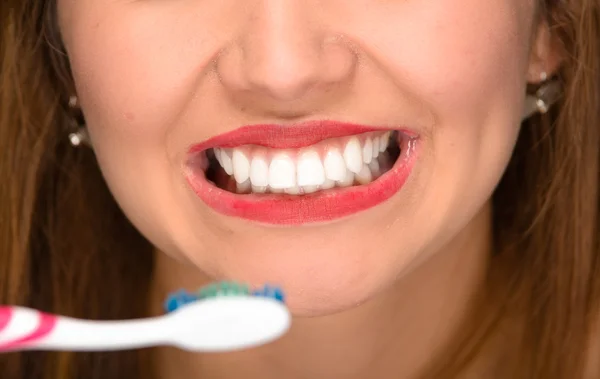 Крупный план молодая женщина рот показывая белые здоровые зубы и держа зубную щетку впереди — стоковое фото