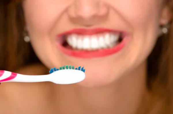 Primer plano de la boca de las mujeres jóvenes mostrando los dientes blancos sanos y sosteniendo el cepillo de dientes en frente — Foto de Stock