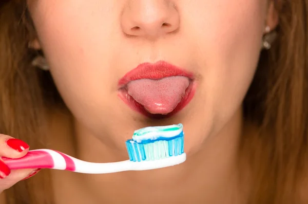 Primer plano las mujeres jóvenes abren la boca con la lengua que sobresale y cepillo de dientes en frente — Foto de Stock