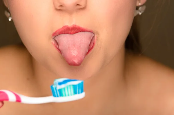 Portre genç kadının açık ağız yapışkanlık dışarı dil ve ön diş fırçası ile — Stok fotoğraf
