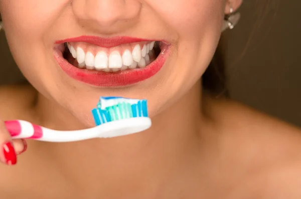 Primer plano de la boca de las mujeres jóvenes mostrando los dientes blancos sanos y sosteniendo el cepillo de dientes en frente — Foto de Stock