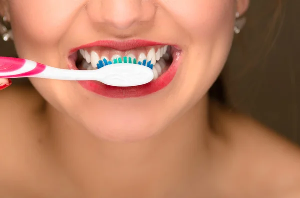 Крупный план молодых женщин рот и белые зубы, с помощью зубной щетки — стоковое фото