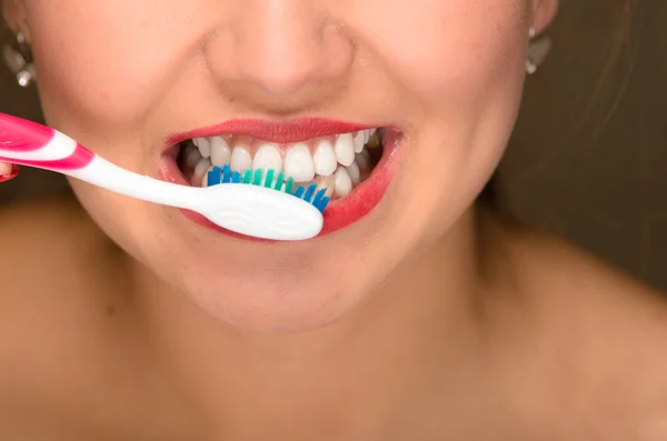 Крупный план молодых женщин рот и белые зубы, с помощью зубной щетки — стоковое фото
