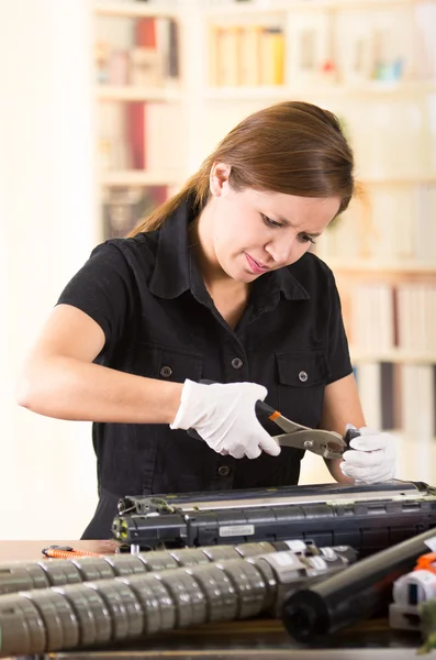 Mulher jovem vestindo camisa preta realizando mudança de toner e manutenção da impressora, expressões faciais concentradas — Fotografia de Stock