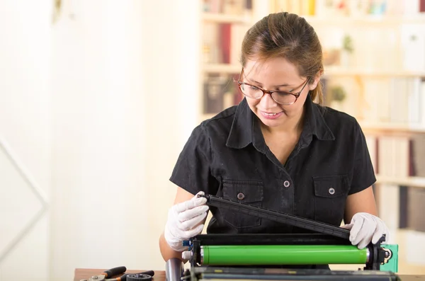 Mulher jovem vestindo camisa preta realizando mudança de toner e manutenção da impressora, expressões faciais concentradas — Fotografia de Stock