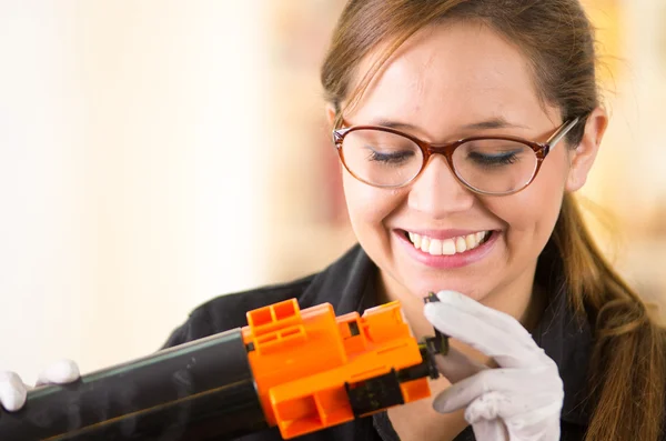 Jovem mulher vestindo camisa preta realizando mudança de toner e manutenção da impressora, atitude positiva sorrindo — Fotografia de Stock