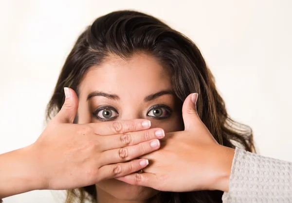 Headshot aantrekkelijke brunette geconfronteerd met camera dekking van de helft van haar gezicht met behulp van beide handen, witte studio achtergrond — Stockfoto