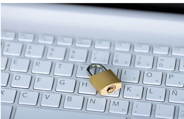 Pequeño candado sentado en el teclado del ordenador blanco, concepto de seguridad en línea — Foto de Stock