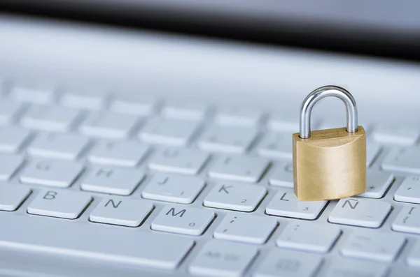 Pequeño candado sentado en el teclado del ordenador blanco, concepto de seguridad en línea — Foto de Stock