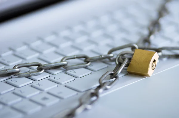 Padlock with metal chain hooked and locked across computer keyboard, internet security concept — Stock Photo, Image