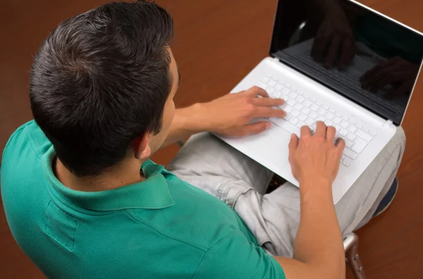 Homme assis et travaillant en utilisant un ordinateur portable blanc vu d'en haut avec les mains tapant sur le clavier — Photo
