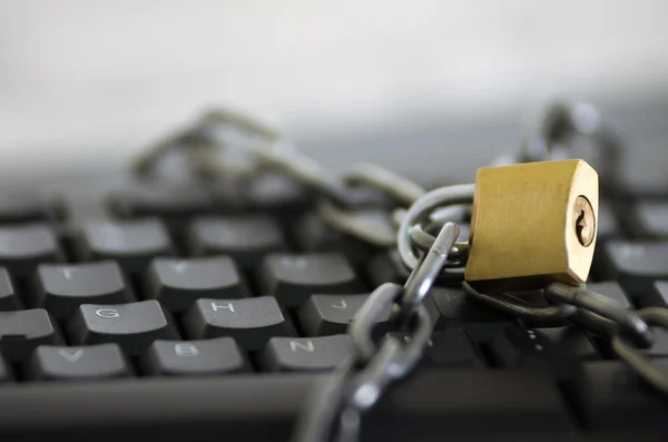 Padlock with metal chain hooked and locked across computer keyboard, internet security concept — Stock Photo, Image